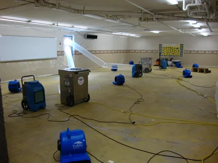 Edmond water damage restoration team setting up commercial air movers and dehumidifiers in flooded basement