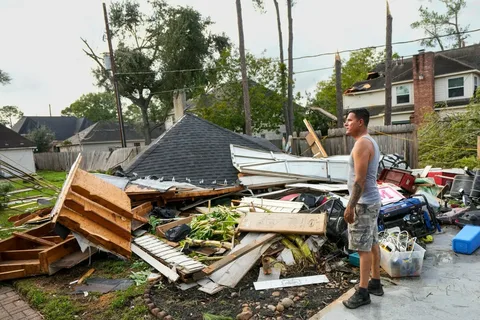 Technicians removing fallen tree from house roof during urgent storm damage cleanup