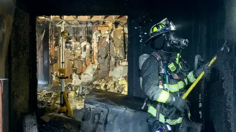 Firefighter inspecting heavily burned interior structure after residential fire before fire damage restoration in Edmond